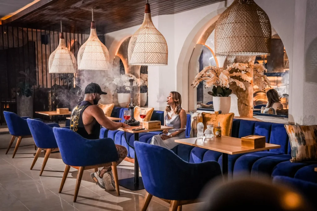 A couple enjoying a smooth shisha session inside the beautifully designed Eden Hookah Club in Ubud, a top spot when looking for where to smoke & buy Mezza in Bali.