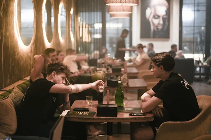 Two friends hanging out and chatting at a table inside the lively Eden Hookah Club Uluwatu, a highly recommended venue for where to smoke & buy Mezza in Bali.