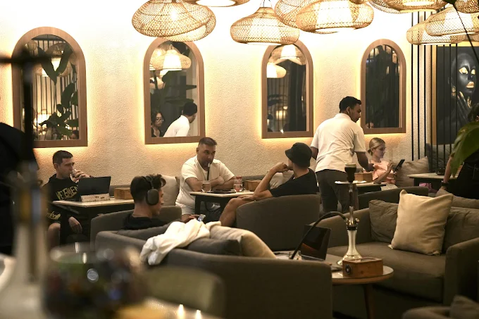 A cozy scene at Eden Hookah Club Canggu with guests working on laptops and relaxing with hookahs, an ideal laid-back spot for where to smoke & buy Mezza in Bali.