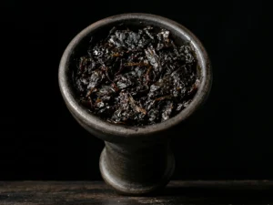 A close-up look at a classic clay hookah bowl that has been perfectly and densely packed with sticky, rich dark leaf shisha.
